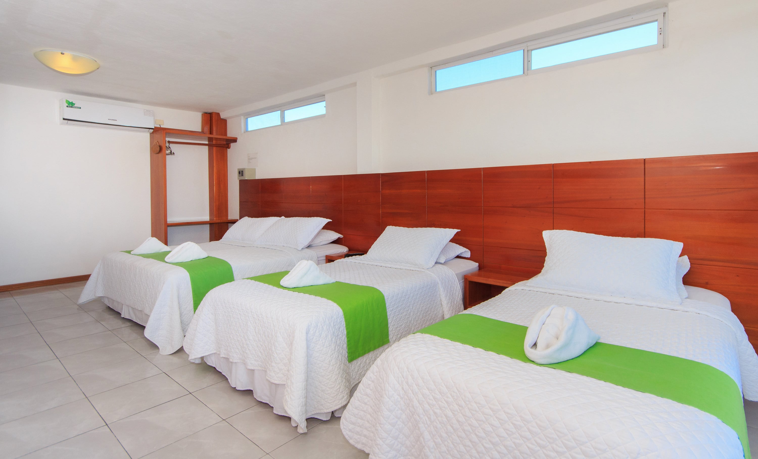 Triple-bed room with wooden furniture, clean decor, and ample space.